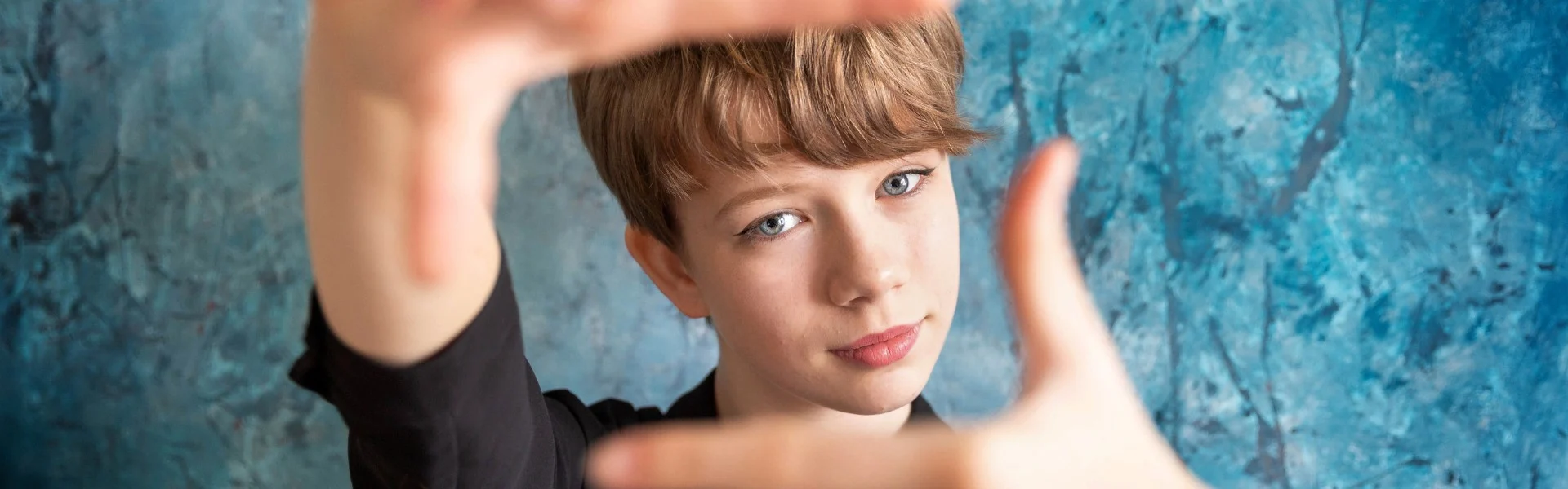 Ein junges Mädchen schaut durch die eigenen Hände, mit den Fingern formt sie einen Bildschirm. Link zum Projekt