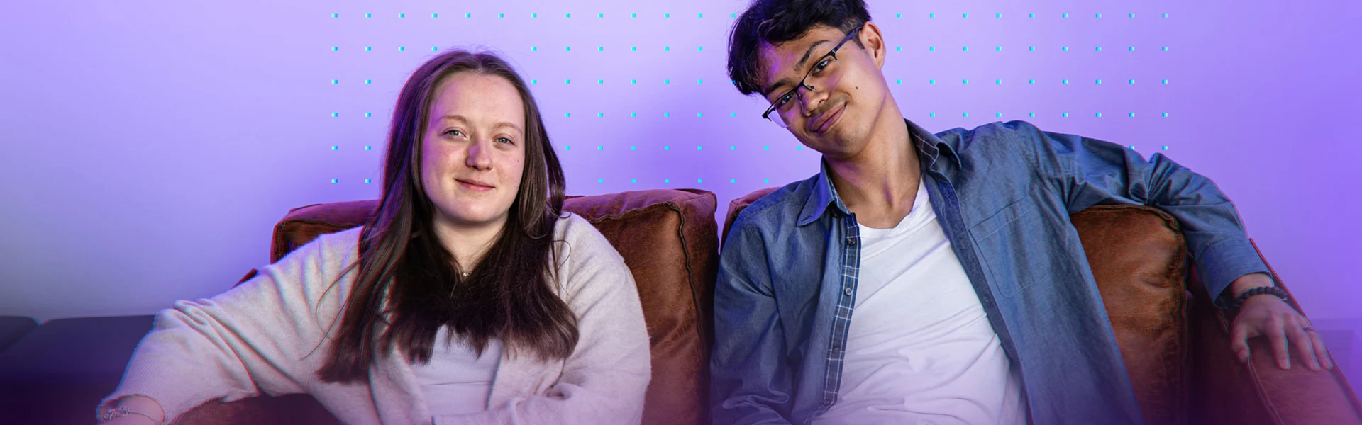 Zwei Jugendliche sitzen nebeneinander auf einem Sofa