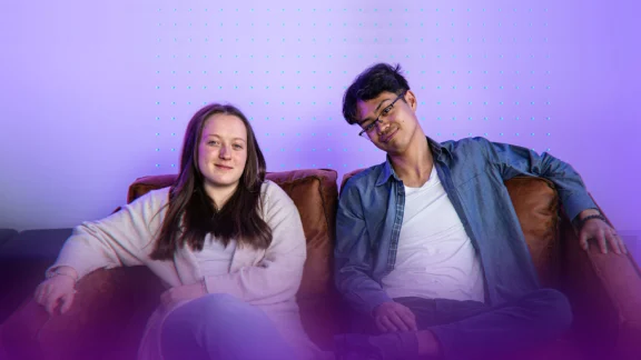 Zwei Jugendliche sitzen nebeneinander auf einem Sofa