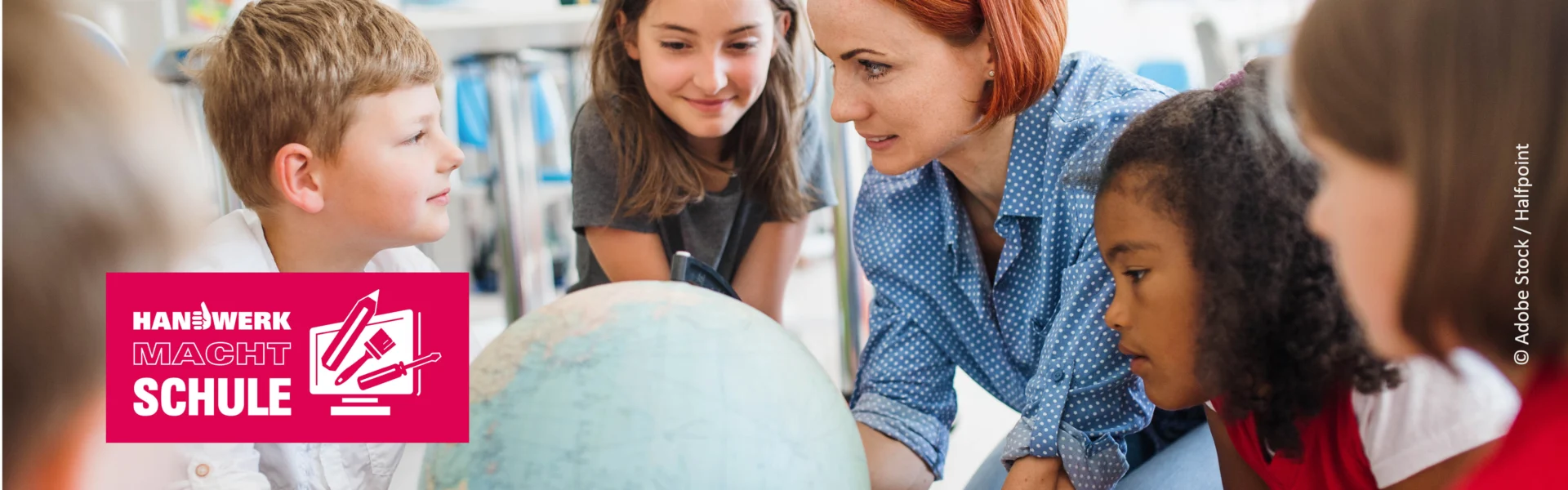 Lehrerin betrachtet mit drei Schüler:innen einen Globus