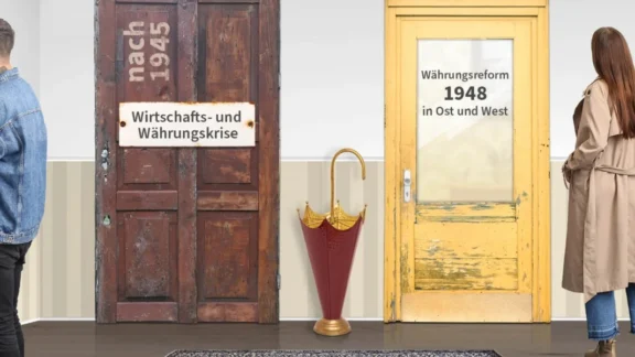In einem Raum stehen ein Mann und eine Frau. Auf vier verschiedenen Türen stehen die jeweiligen Themen. Über einen Rucksack mit Büchern unten rechts kommt man zum Unterrichtsmaterial. Link zum Projekt "Von Inflation und Stabilität".